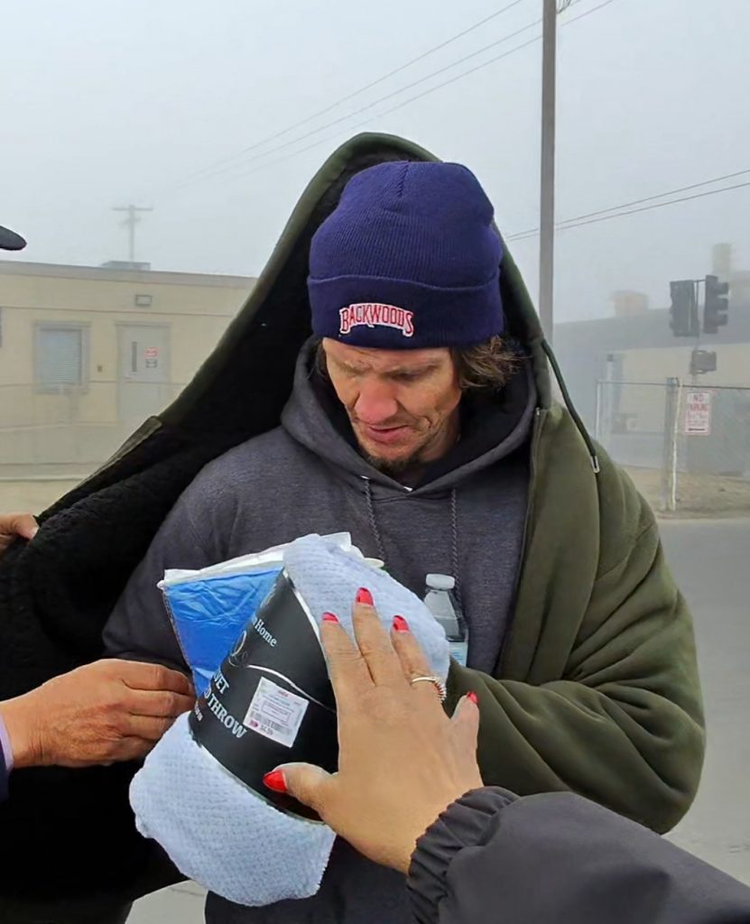 Outreach team members from Hart to Hart 4 U providing a warm jacket and a blanket to Christopher on a foggy morning.